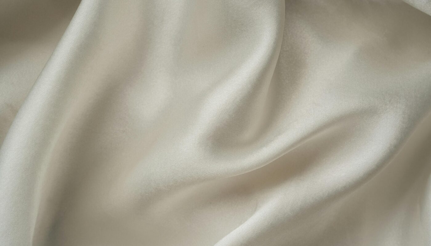 Close-up of smooth white silk fabric with soft folds and gentle draping.